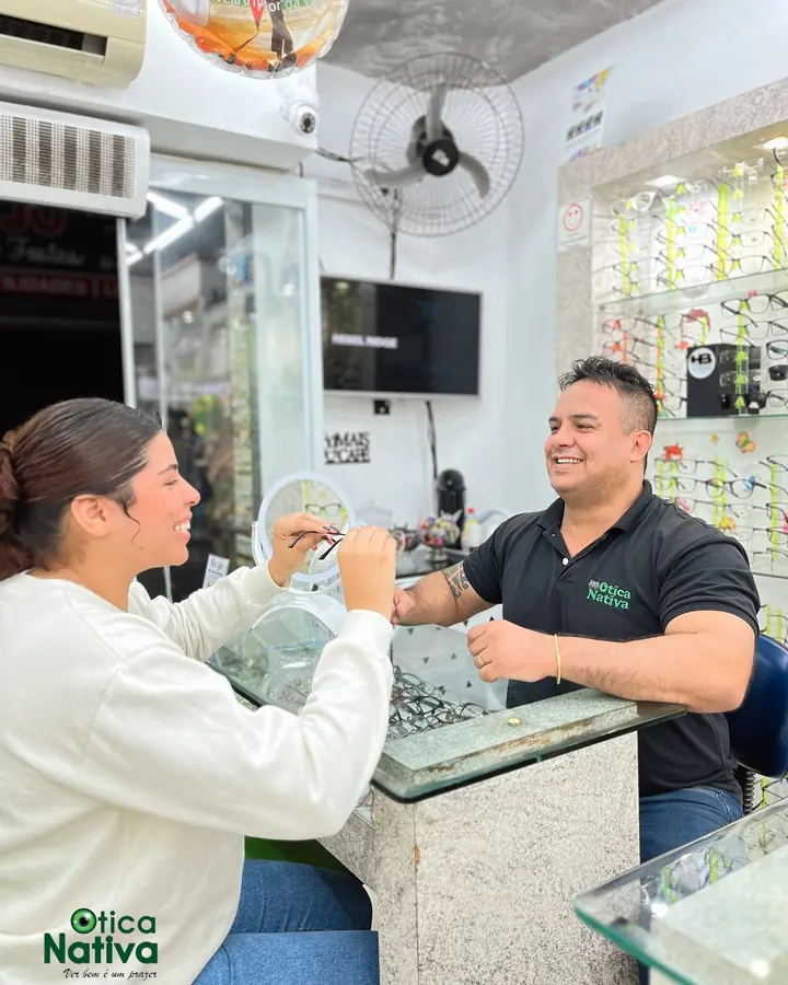 Cliente escolhendo uma armação com a ajuda de um atendente no balcão da Ótica Nativa